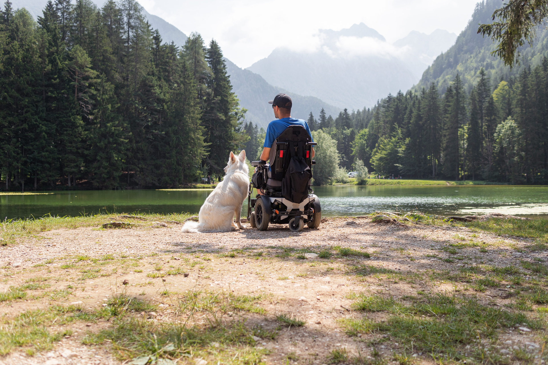 Mann im Elektrorollstuhl mit Hund am See