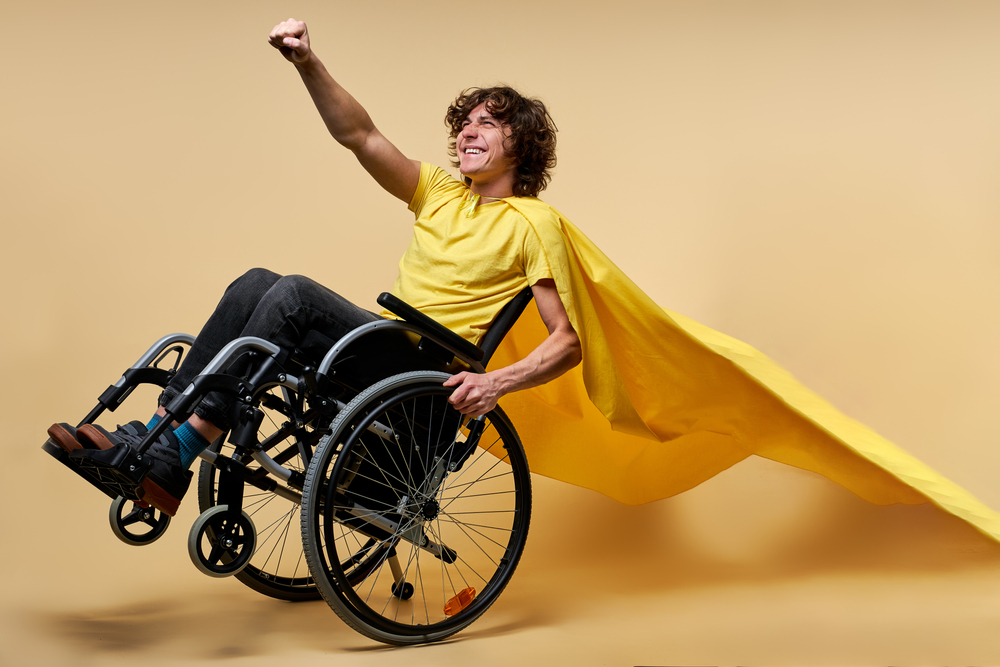 Junger Mann im Rollstuhl mit Superheldenumhang
